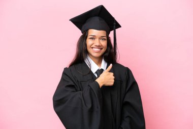 Kolombiyalı genç bir üniversite mezunu pembe arka planda izole edilmiş bir şekilde el kol hareketi yapıyor.