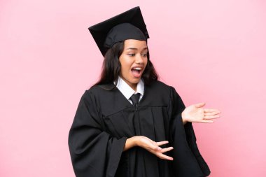 Kolombiyalı genç bir üniversite mezunu. Pembe arka planda izole edilmiş. Yüz ifadesi şaşırtıcıydı.