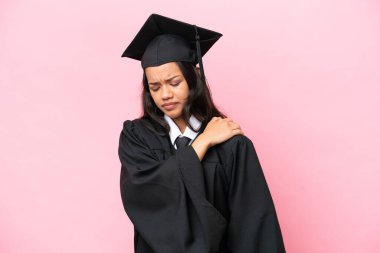 Kolombiyalı genç bir üniversite mezunu. Pembe arka planda izole edilmiş. Omuz ağrısı çekiyor.