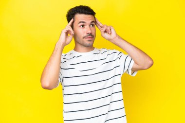 Şüpheve düşünme sahip izole sarı arka plan üzerinde Genç yakışıklı adam