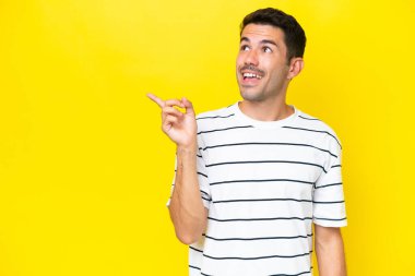 Soyutlanmış sarı arka planı olan genç yakışıklı bir adam parmağını kaldırarak çözümü bulmaya çalışıyor.