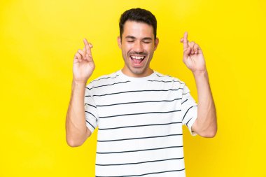 Parmakları geçiş ile izole sarı arka plan üzerinde genç yakışıklı adam