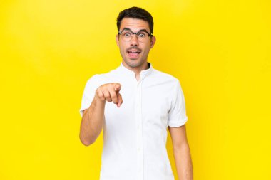 Izole sarı arka plan üzerinde genç yakışıklı adam şaşırttı ve ön işaret