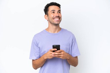 İzole edilmiş beyaz arka planı olan genç yakışıklı bir adam cep telefonu kullanıyor ve