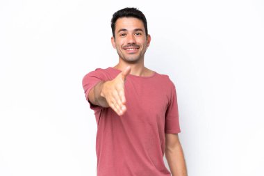 Soyutlanmış beyaz arka planda genç yakışıklı adam iyi bir anlaşma için el sıkışıyor.