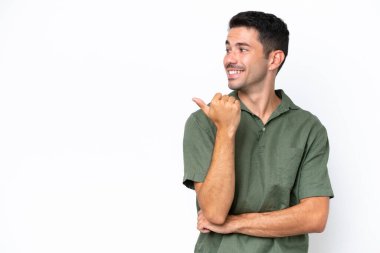Soyutlanmış beyaz arka planda genç yakışıklı bir adam bir ürün sunmak için kenarı işaret ediyor.