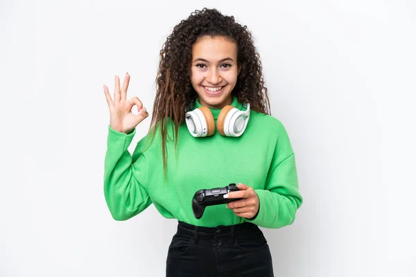 年轻的阿拉伯妇女正在玩一个视频游戏控制器 它被隔离在白色背景中 用手指显示出确定的标志 — 图库照片