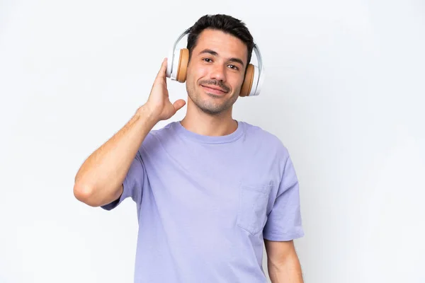 Νέος Όμορφος Άντρας Πάνω Από Απομονωμένο Λευκό Φόντο Ακούγοντας Μουσική — Φωτογραφία Αρχείου