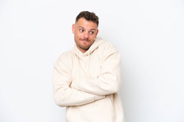 Beyaz arka plandaki beyaz tenli yakışıklı adam omuzlarını kaldırırken şüpheyle hareket ediyor.