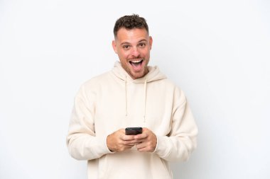 Beyaz arka planda izole edilmiş beyaz, yakışıklı genç bir adam şaşırdı ve bir mesaj gönderiyor.