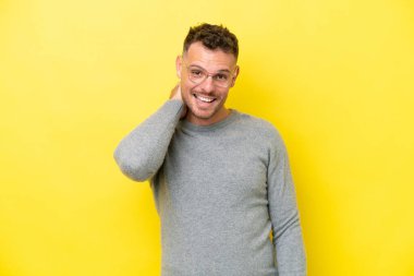 Sarı arka planda izole edilmiş genç beyaz yakışıklı adam gülüyor.