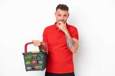Beyaz arka planda izole edilmiş yiyecek dolu bir alışveriş sepeti tutan beyaz bir adam.