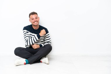 Yerde oturan genç adam beyaz arka planda tek başına zaferi kutluyor.