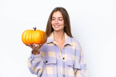 Beyaz arka planda izole edilmiş bir balkabağı tutan güzel bir kadın. Mutlu bir ifadeyle.