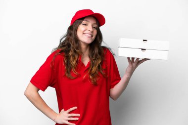 Pizza dağıtan kadın iş üniformalı beyaz arka planda izole edilmiş pizza kutuları alıyor kolları kalçasında ve gülümsüyor.
