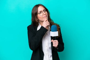 Genç TV sunucusu kadın mavi arka planda izole edilmiş ve yukarı bakıyor