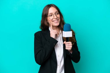 Genç TV sunucusu kadın, mavi arka planda izole edilmiş bir şekilde bakarken bir fikir düşünüyor.