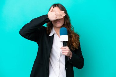 Genç TV sunucusu kadın, mavi arka planda tek başına, gözleri elleriyle kapatıyor. Bir şey görmek istemiyorum.