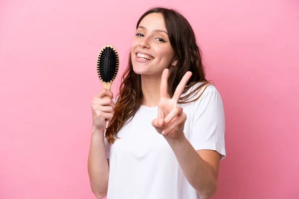 Mujer Joven Caucásica Con Peine Aislado Sobre Fondo Rosa Sonriendo —  Fotos de Stock