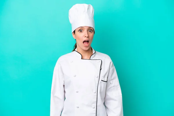 Young caucasian chef woman isolated on blue background with surprise facial expression