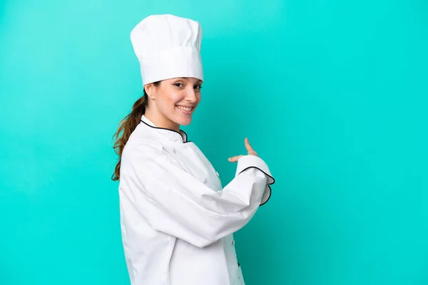 Joven Mujer Chef Caucásica Aislada Sobre Fondo Azul Apuntando Hacia —  Fotos de Stock