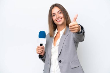Genç TV sunucusu beyaz arka planda izole edilmiş beyaz bir kadın. Başparmakları havada çünkü iyi bir şey oldu.