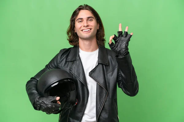 若いですハンサムな男とともにオートバイヘルメット隔離上の緑色の背景ショーOk Signとともに指 — ストック写真