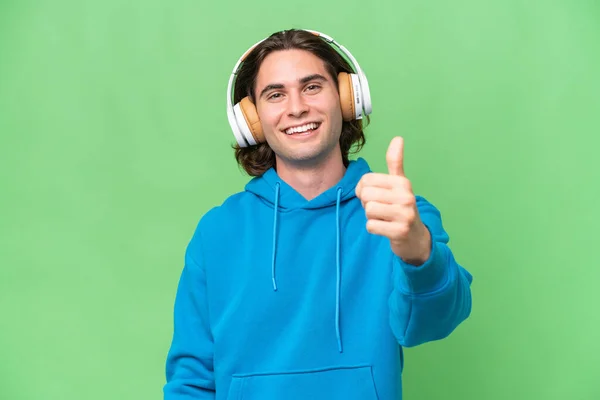 Νεαρός Όμορφος Άνδρας Απομονωμένος Πράσινο Chroma Φόντο Ακούγοντας Μουσική Και — Φωτογραφία Αρχείου