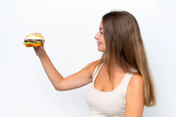 Jonge Mooie Vrouw Houden Een Hamburger Geïsoleerd Witte Achtergrond Met — Stockfoto