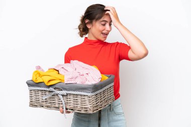 Young caucasian woman holding a clothes basket isolated on white background smiling a lot