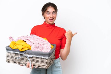 Beyaz arka planda izole edilmiş çamaşır sepeti tutan beyaz bir kadın bir ürünü sunmak için kenarı işaret ediyor.