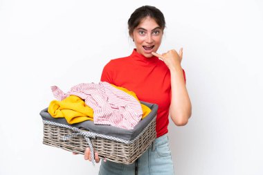 Beyaz arka planda izole edilmiş çamaşır sepeti tutan beyaz bir kadın telefon jesti yapıyor. Bana geri dönüş işareti ver.