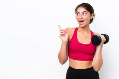 Beyaz arka planda halter kaldıran beyaz tenli genç bir kadın çözümü bulmak için parmağını kaldırarak halter kaldırıyor.