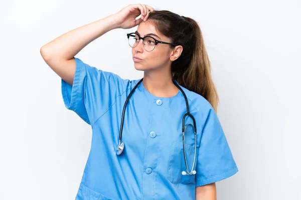 年轻的护士医生妇女 背景为白色 有疑问 面部表情混乱 — 图库照片