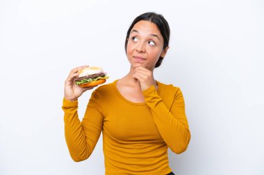 Beyaz arka planda izole edilmiş bir burger tutan genç İspanyol kadın...