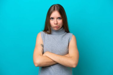 Genç Litvanyalı kadın mutsuz bir ifadeyle mavi arka planda izole edilmiş.