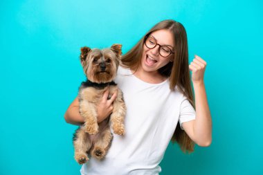 Mavi arka planda köpeği tutan Litvanyalı genç bir kadın zaferi kutluyor.