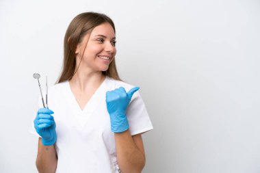Beyaz arka planda izole edilmiş aletleri tutan dişçi kadın bir ürünü sunmak için kenarı işaret ediyor