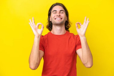 Caucasian handsome man isolated on yellow background in zen pose