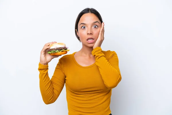 Młoda Latynoska Kobieta Trzyma Hamburgera Białym Tle Zaskoczeniem Wstrząśniętym Wyrazem — Zdjęcie stockowe