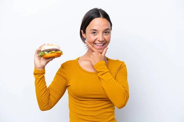 Młoda Latynoska Kobieta Trzyma Hamburgera Białym Tle Szczęśliwa Uśmiechnięta — Zdjęcie stockowe