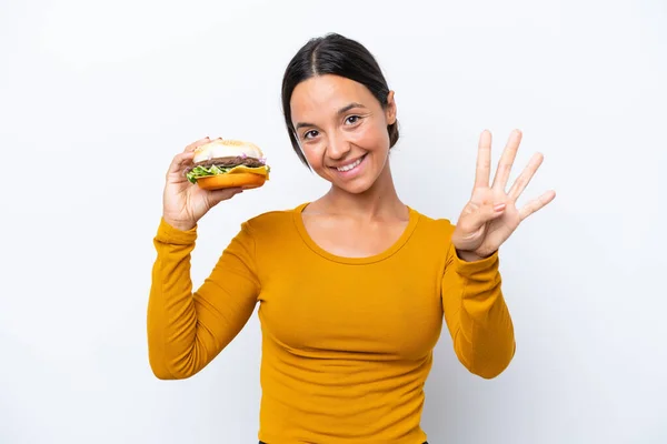 Młoda Latynoska Kobieta Trzymająca Hamburgera Białym Tle Szczęśliwa Licząca Cztery — Zdjęcie stockowe