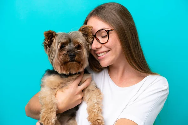 Young Lithuanian woman holding a dog isolated on blue background