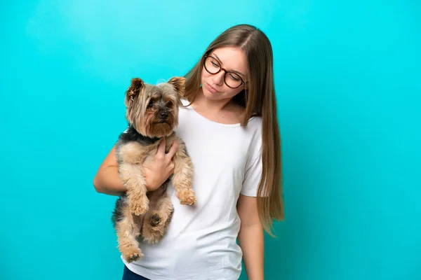 Young Lithuanian woman holding a dog isolated on blue background with sad expression