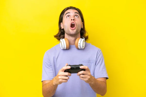 Молодой Красивый Белый Мужчина Играет Контроллером Видеоигры Над Изолированным Желтом — стоковое фото