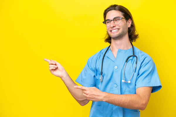 Young surgeon caucasian man isolated on yellow background pointing finger to the side and presenting a product