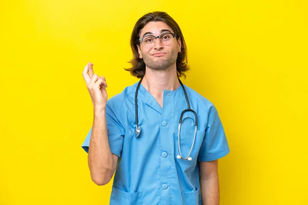 Young Surgeon Caucasian Man Isolated Yellow Background Fingers Crossing Wishing — Stock Photo, Image