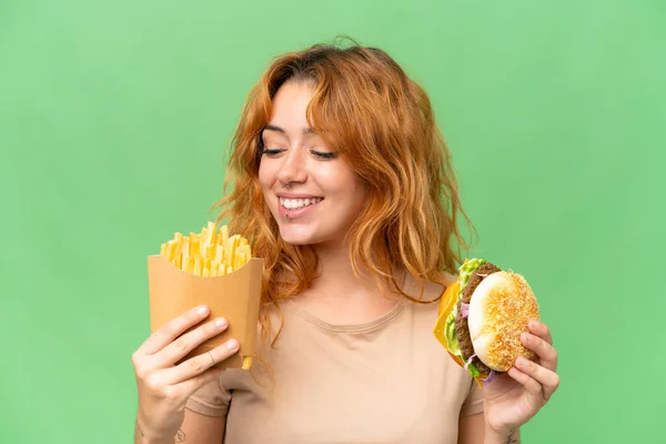 若いです白人女性を保持揚げチップとバーガー隔離上の緑の画面クロマキー背景 — ストック写真