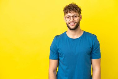 Sarı arka planda izole edilmiş yakışıklı beyaz adam gülüyor.