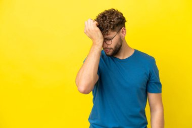 Sarı arka planda başağrısı olan yakışıklı, beyaz bir adam.